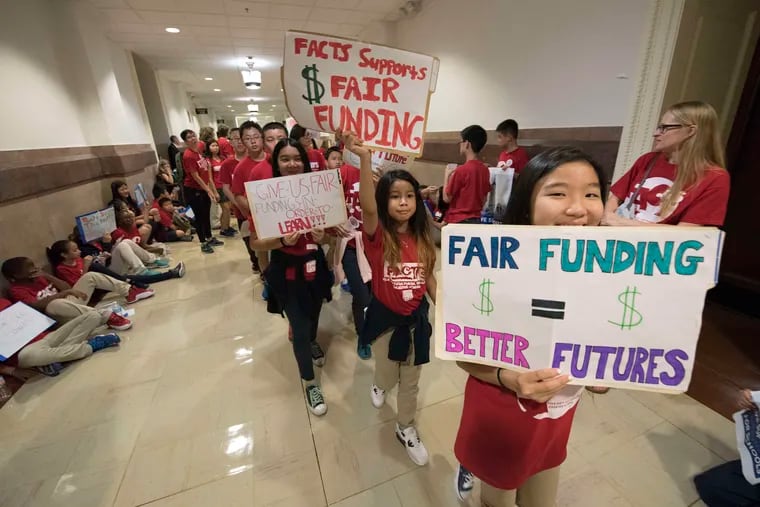 Students from the Folk Arts-Cultural Treasures Charter School in Philadelphia march with signs outside the state Supreme Court's chamber in Philadelphia's City Hall. Plaintiffs argue the state's education-funding system is unfair.