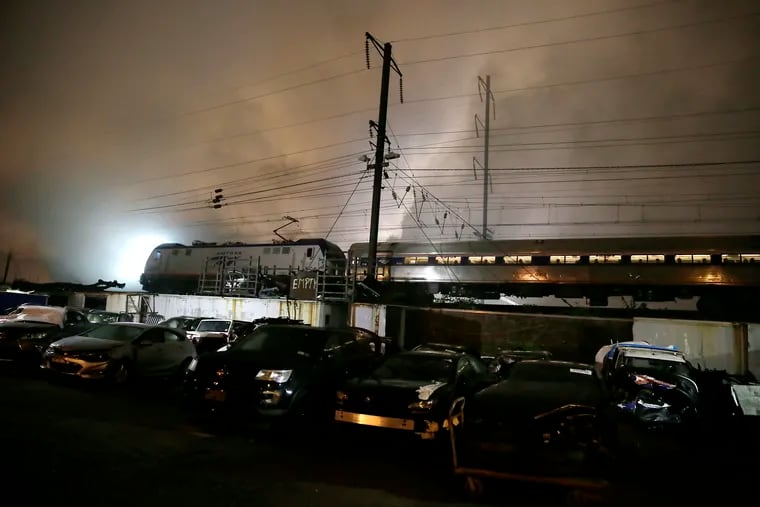 An Amtrak train passes slowly by the junkyard fire near Torresdale and Adams Avenues in Philadelphia's Frankford section Sunday night.