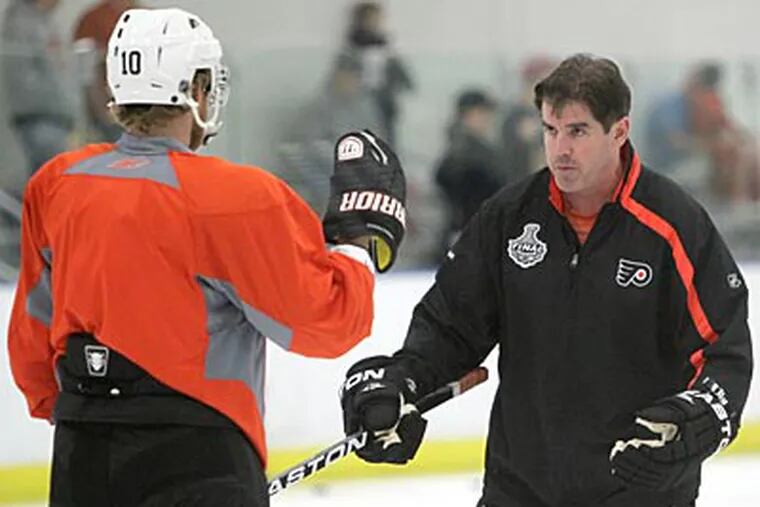 Flyers coach Peter Laviolette talks with forward Kris Versteeg during practice on Thursday. (Charles Fox/Staff Photographer)