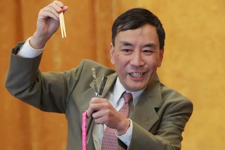 Rowan University history professor Qingjia Edward Wang shows how it’s done with chopsticks, whether the disposable restaurant kind, or the lacquered and painted variety. (MICHAEL BRYANT / Staff Photographer)