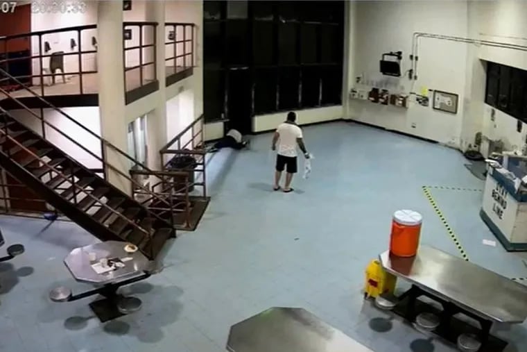 A still image depicting part of the Philadelphia jail escape on May 7, 2023. One of the escapees can be seen crawling on the ground at the top of the photo, while another prisoner acts as a lookout.