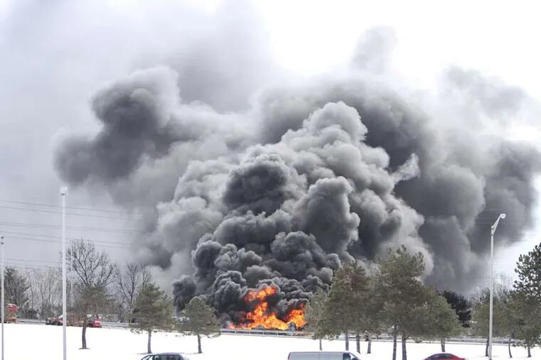 A tanker truck burns out of control, Monday Feb. 23, 2015, after it overturned on an off ramp in Pennsauken NJ.  (For the Inquirer and Daily News/ Joseph Kaczmarek)