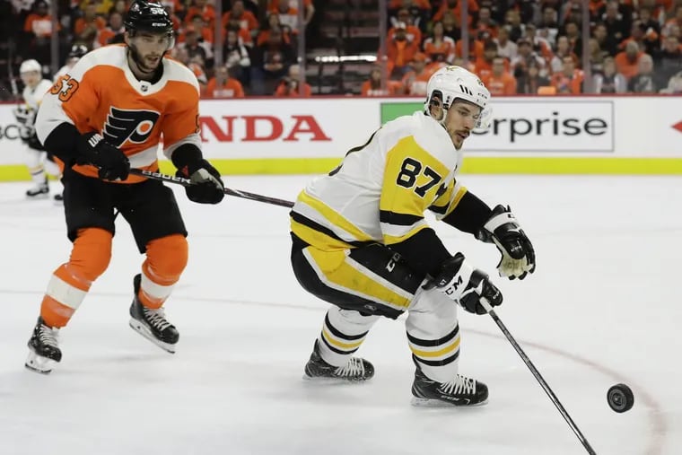 Penguins center Sidney Crosby skating with the puck against Flyers defenseman Shayne Gostisbehere on Sunday. Pittsburgh leads the series, two games to one.