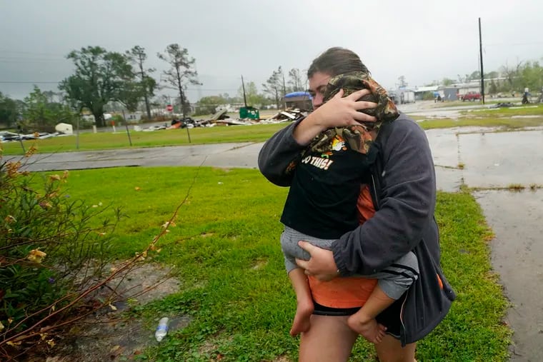 Danielle Fontenot runs to a relative's home in the rain with her son Hunter ahead of Hurricane Delta in Lake Charles, La.