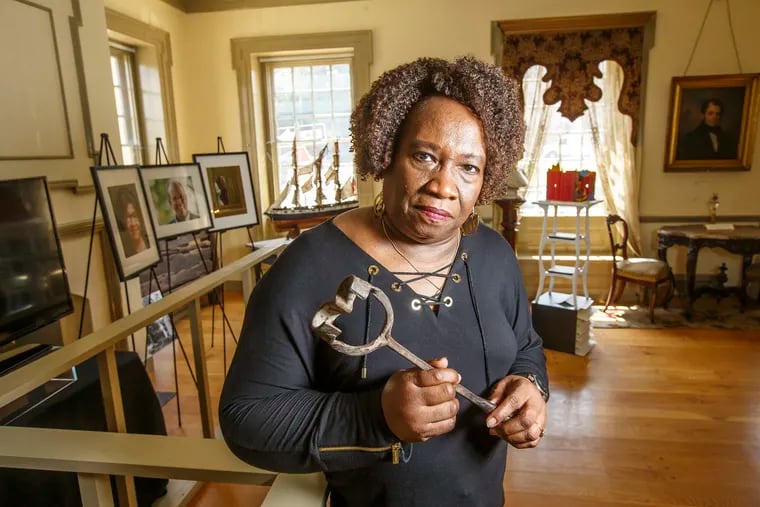Gwen Ragsdale, center, holds a branding iron used to brand slaves in the earlt 1800's as she stands in the Germantown Historical Society, which will give exhibit space to the Lest We Forget Black Holocaust Slavery Museum, until it can find a permanent home. MICHAEL BRYANT / Staff Photographer