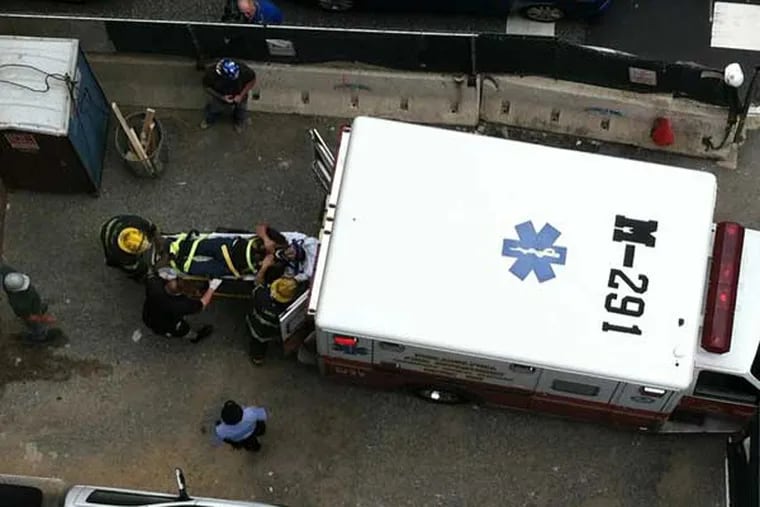 A man injured in a fall at a construction site at 15th and Arch streets in Center City is put into an ambulance.