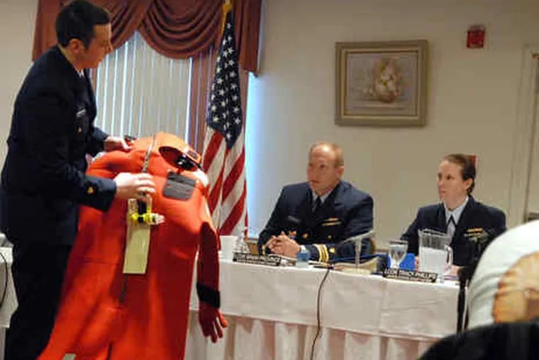 On the first day of a Coast Guard inquiry, rescue crew member David Downham holds a survival suit from the sunken boat. Its owner is permitted to question witnesses.