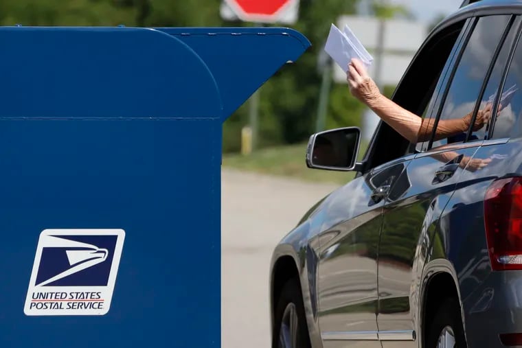 A person deposits mail in a box outside the Post Office in Cranberry Township, Pa., in August.