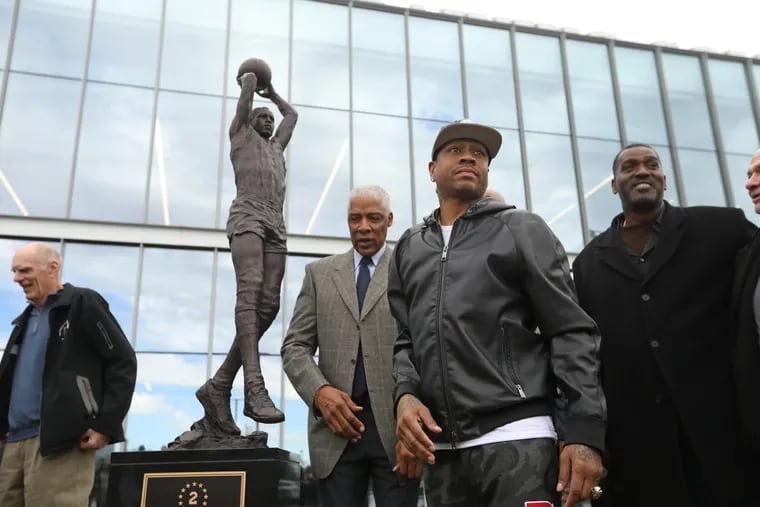 Julius Erving (center, rear), Allen Iverson (center, right) and other teammates gather around the statue of former 76ers great Moses Malone on Friday at the Sixers' practice facility in Camden.
