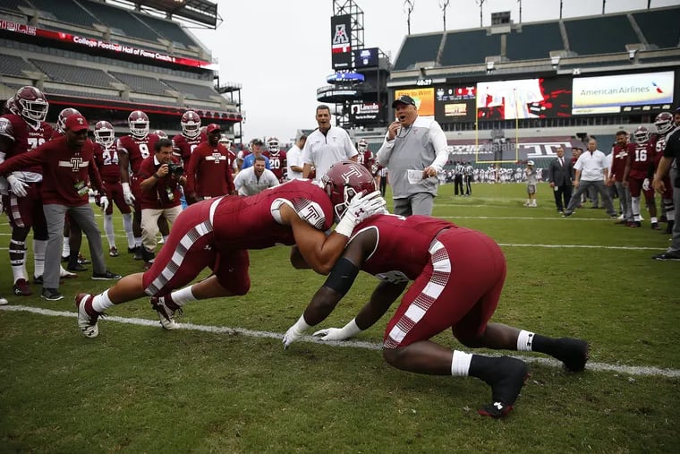Temple's head coach Geoff Collins, center background, watches Dan Archibong, left, Michael Dogbe, right, warm up before the Temple Owls play the UCONN Huskies in Philadelphia, PA on October 14, 2017. DAVID MAIALETTI / Staff Photographer
