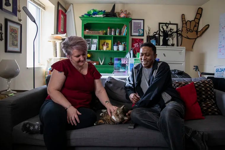 Vicki Landers, 51, of North Philadelphia, executive director of Disability Pride Philadelphia, and Renato "Ray" Horton, 51, pose on their couch with Landers' cat Damien, one of their emotional support animals, in their apartment on Wednesday, Feb. 12. “To me, Damien is family, calming, and he knows when I need him,” Landers said.