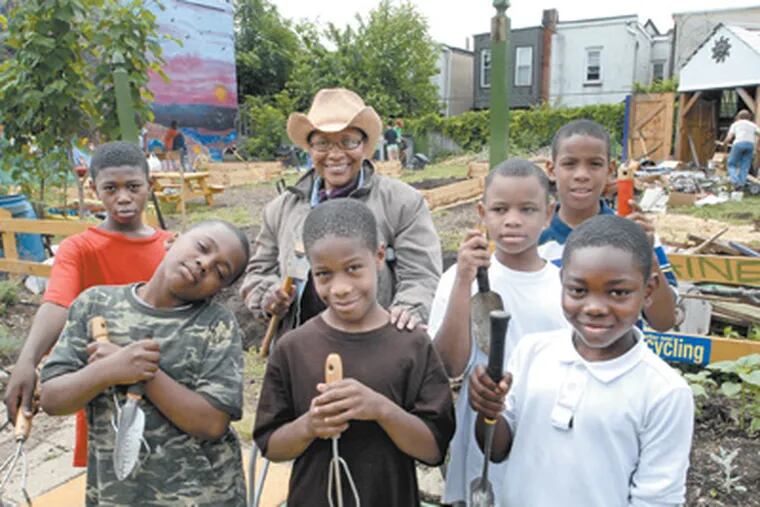 Gardener Vanoka Morris-Smith (in hat) and some of her friends from Blaine Elementary School in the Strawberry Mansion community garden they helped her restore after it was ravaged by neighborhood vandals. (April Saul / Staff Photographer)