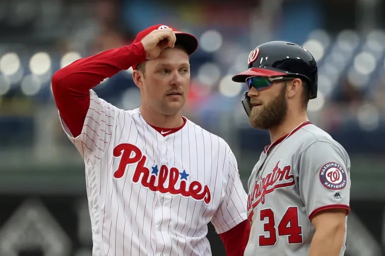 Rhys Hoskins, left, of the Phillies and Bryce Harper of the Nationals talk as the umpire crew reviews the replay of a play at Citizens Bank Park on Sept. 11, 2018.   CHARLES FOX / Staff Photographer