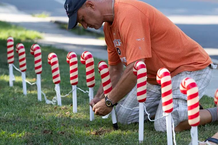 Known for going all out with their holiday decorations in December, Perry and Alyse Katsapis decided to have Christmas in July to brighten everyone’s spirits during the COVID-19 pandemic by decorating their Wallingford, Delaware County home
  Perry sets up blinking candy canes on July 28, 2020.  The decorations will be up till the end of the month.