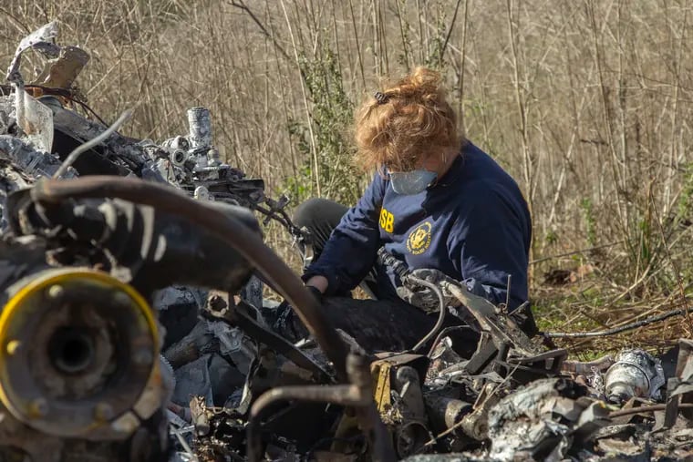 In this image provided by the National Transportation Safety Board, NTSB investigator Carol Hogan examines wreckage as part of the NTSB’s investigation.
