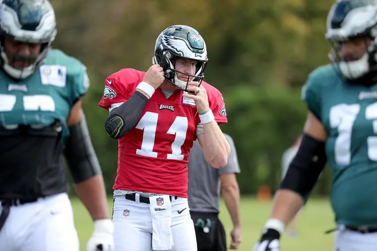 Eagles Carson Wentz, center, adjusts his helmet during Eagles practice at the NovaCare Complex in Philadelphia, PA on October 3, 2018. DAVID MAIALETTI / Staff Photographer