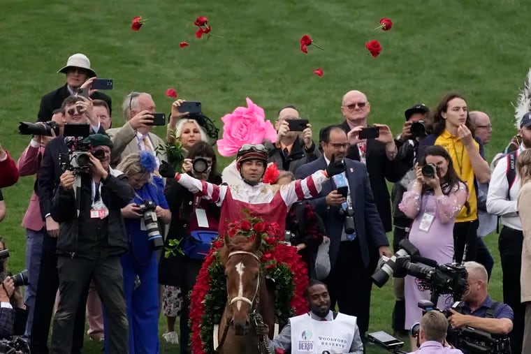Jockey Sonny Leon tosses roses into the air as he rides long shot Rich Strike to the winner’s circle after capturing the Kentucky Derby.