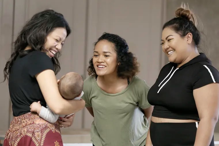 Phorllie Tsen (left) holds Melinda Son's 7-month-old son Adrian Inthathirath as Lanica Angpak (middle) and Son entertain him prior to their CAGE (Cambodian American Girls Empowering) dance workshop at Bok Bar in South Philadelphia.