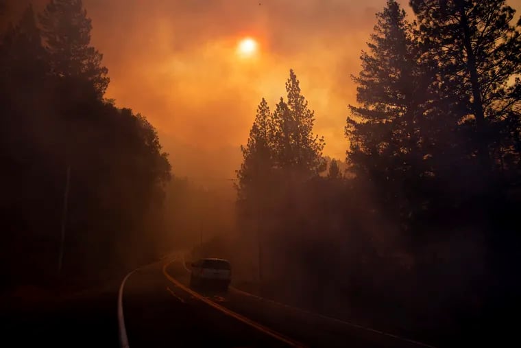A vehicle drives through smoke from a wildfire near Pulga, Calif., Sunday, Nov. 11, 2018. (AP Photo/Noah Berger)