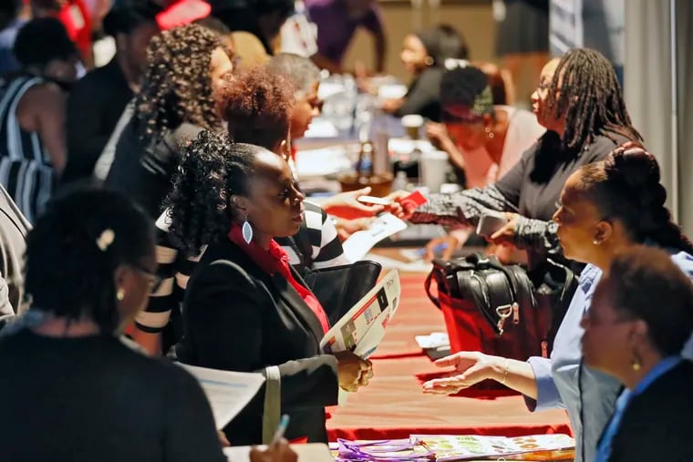 FILE - In this Aug. 14, 2019, file photo company representatives from Verizon, Goodwill, Kaiser Permanente and UPS, right, talk with potential applicants during a job and resource fair in Atlanta. On Friday, Sept. 6, the U.S. government issues the August jobs report.