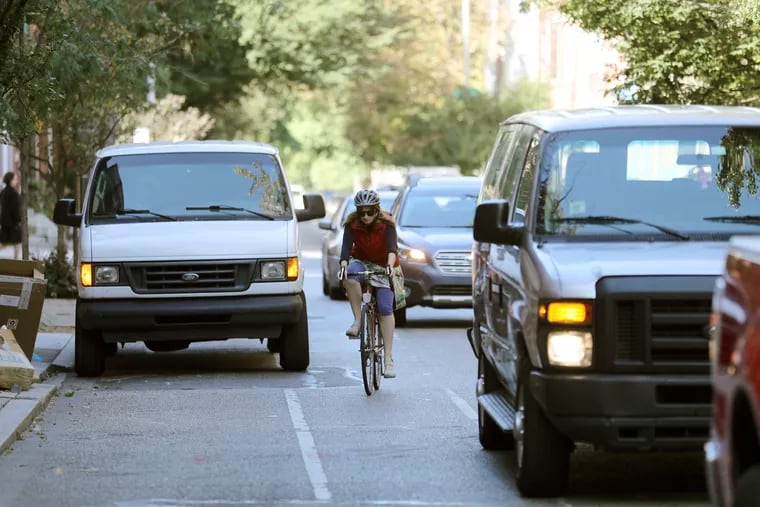 A bicyclist weaving into traffic to avoid a parked van in the bike lane on on Pine Street. Drivers will now be ticketed for parking in bike lanes.