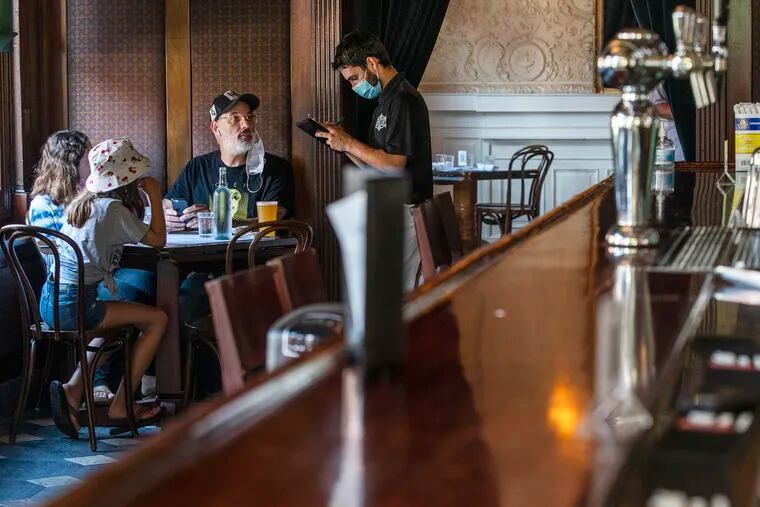 A waiter in a protective face mask takes a customer's order during lunch at a restaurant in Hoboken, N.J., in September.