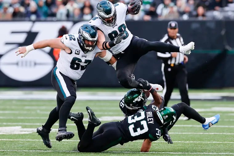 Eagles tight end Dallas Goedert leaps with, an assist from teammate center Jason Kelce, past New York Jets.