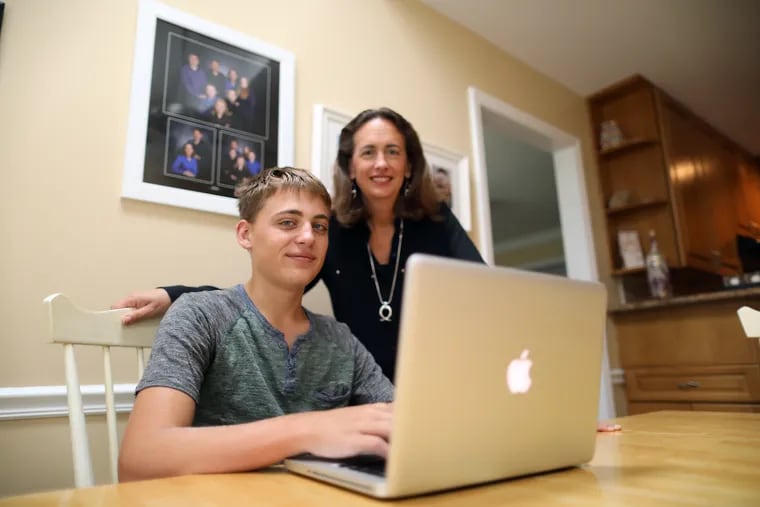 Kevin Smith and his mother Kim at kitchen table with his laptop. Soon at Garnet Valley HS students will be able to choose the format of their courses – either in class, online or a blended form of both.