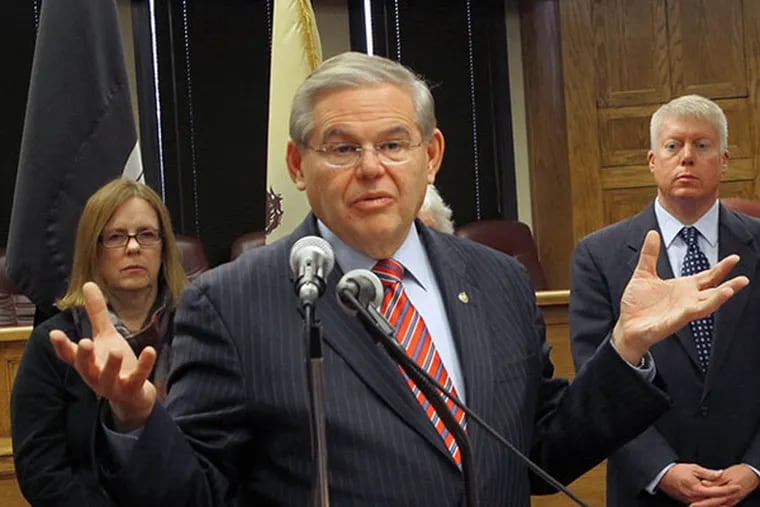 U.S. Sen. Robert Menendez, D-N.J., speaks at a a public hearing on flood insurance rates Thursday, Jan. 2, 2014, in Brick Township, N.J. Peggy Molloy, left, who fears that skyrocketing flood insurance premiums will force her from her Point Pleasant home, and Brick Township Mayor John Ducey, right, stand in background. Menendez is pushing a bill that would delay drastic flood insurance rate increases for up to two years while the federal government studies their affordability and the science behind them. (AP Photo/Wayne Parry)
