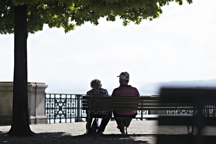 An elderly couple sit on a bench by Lake Zurich in Zurich, Switzerland. 
