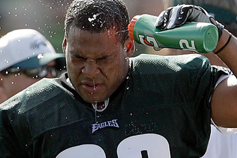 Charles Scott cools off with water during an afternoon practice at training camp.  (Yong Kim/Staff Photographer)