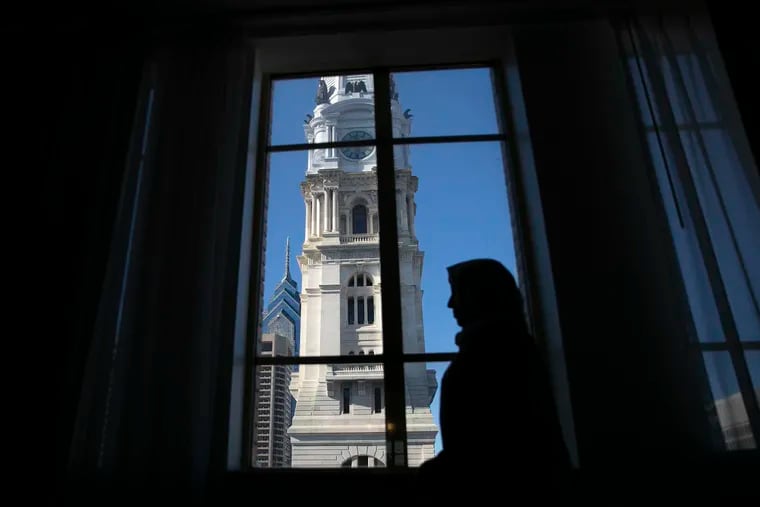 Saharnaaz Muniri, 25, is silhouetted with Philadelphia’s City Hall behind her inside the Residence Inn by Marriott Philadelphia Center City hotel room that she, her parents and siblings lived in for a while after leaving a U.S. military camp on Nov. 23, 2021.