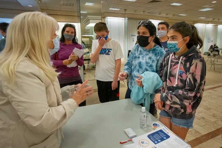 From left are Kathleen Povernick, assisting parents check out after getting their children vaccinated. Also from left are Janine Furia, neighbor kid Sam Baskies, 14, his mom Miriam Baskies, Michael Furia, 13, and Molly Baskies, 12.