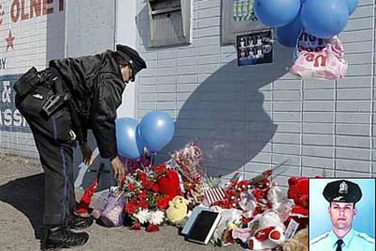 35th District police officer Nannette Taylor fixes a memorial on Sunday to fellow officer John Pawlowski, at Broad and Olney streets near where he was slain. (Akira Suwa / Staff Photographer ).