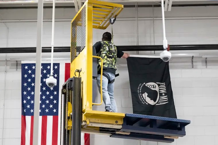 Dan Millard, a Lowe's employee, hangs a POW flag at the Lowe's store in Trevose, Pa. during a POW flag dedication on Friday, Apr 5, 2024.