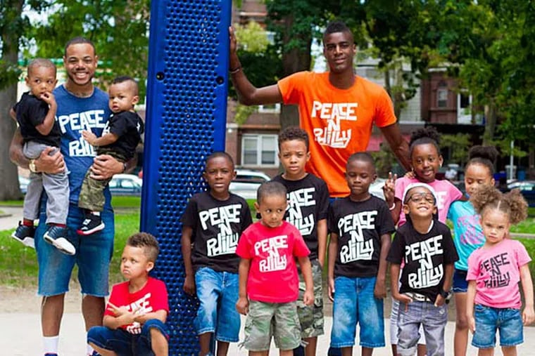 Nehemiah Davis (center) , Police Officer Willie Roundtree, and neighborhood children at Davis' Peace 'N Philly event. Davis also runs a moving and hauling company.