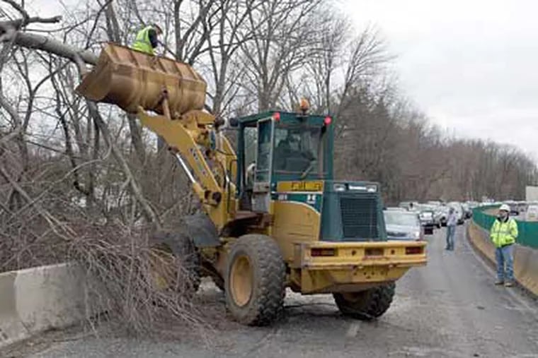 Crews clear away a tree that fell onto the southbound side of route 309 because of wind gusts today. (Dan King / For the Inquirer)