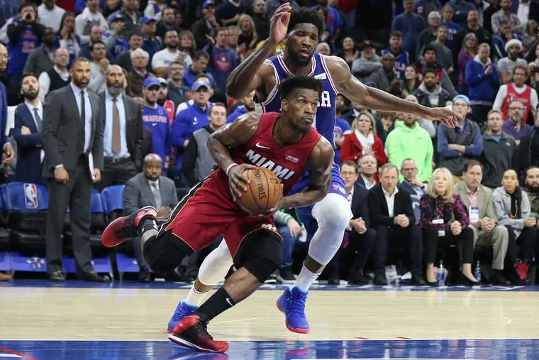 Jimmy Butler, left, of the Heat drives by Joel Embiid of the Sixers during a game at the Wells Fargo Center last December.