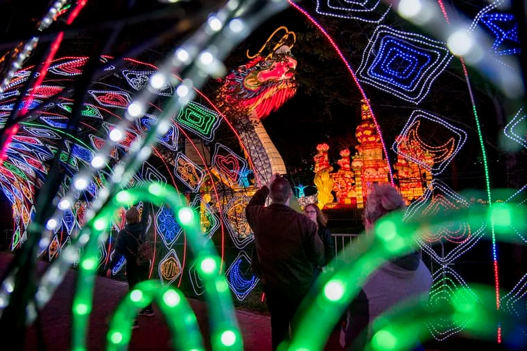VIP guests pause under the "Time Tunnel" archway of lanterns with the "Chinese Dragon" and "Lion Palace Lantern" at rear, during soft opening of the Philadelphia Chinese Lantern Festival in Franklin Square Monday, April 30, 2018.