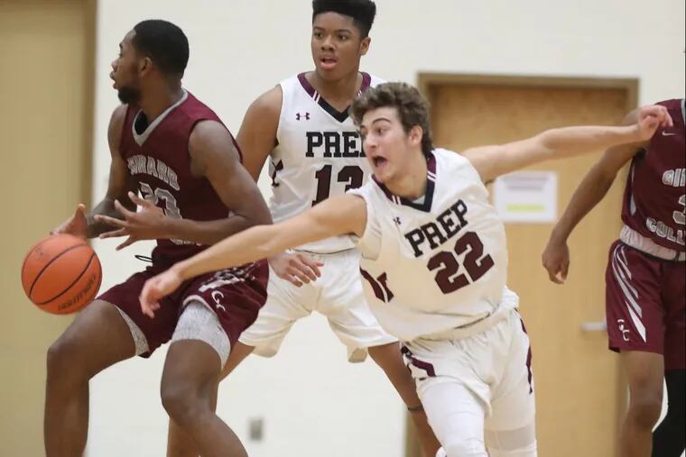 Trevor Wall (right) of St. Joseph’s Prep comes from behind to strip the ball away from Mikeal Jones of Girard College in Friday night’s game. Prep  won, 58-56.