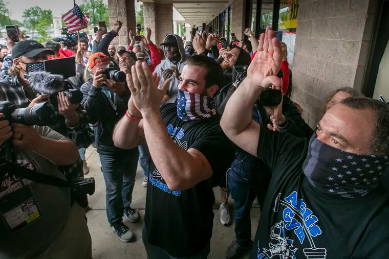 Ian Smith,(center) co-owner of Atilis Gym of Bellmawr, NJ celebrates after being informed by Bellmawr Police that they were in violation of state order, and then the police left. Ian Smith opened his gym against NJ state rules during Covid-19 shutdown.