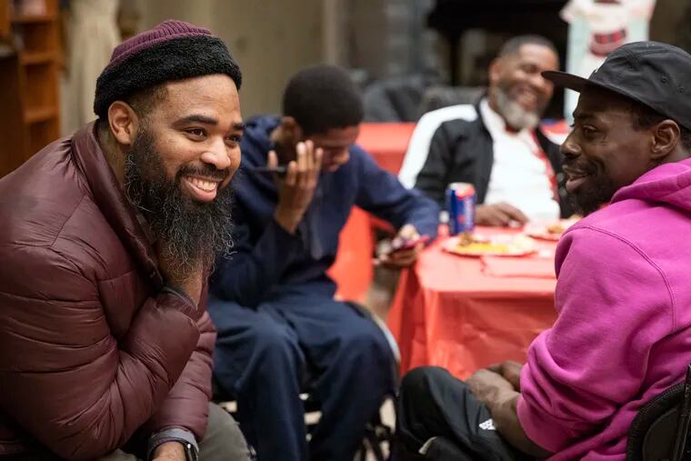 Jalil Frazier, left, laughing with John Muldrow, right, at the Carousel House in West Philadelphia on Dec. 16, 2019. The gunshot survivors group was having a holiday party for its final meeting of the year.