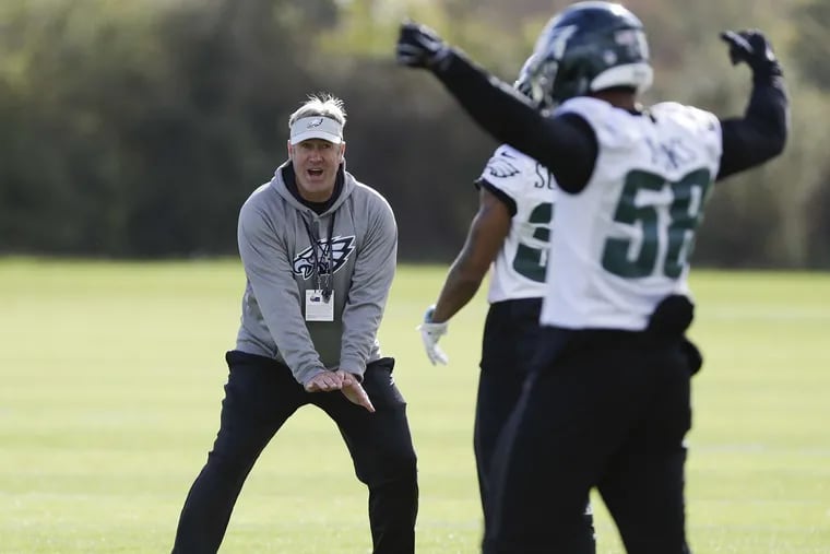 Eagles Head Coach Doug Pederson shows his quarterback stance while player warm-up during practice at the London Irish training ground in Southwest London on Friday, October 26, 2018. YONG KIM / Staff Photographer