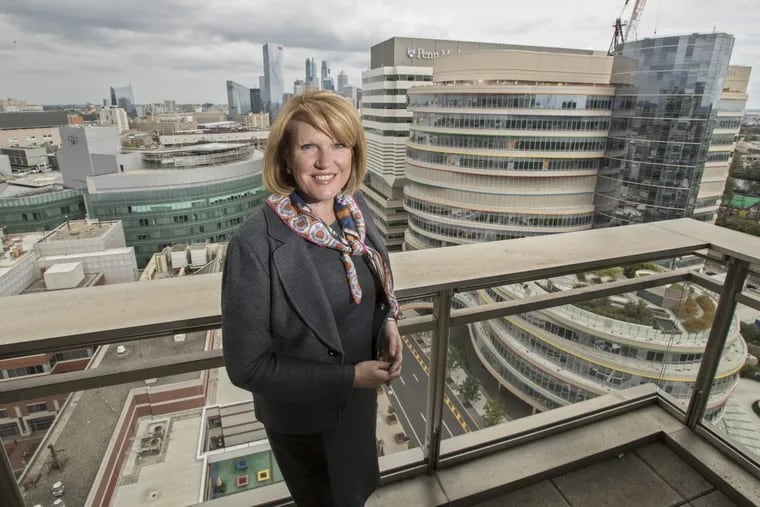 Madeline Bell, CHOP president and CEO,   shown with views of the Buerger Center for Advanced Pediatric Care on the right and the main CHOP building on the left.