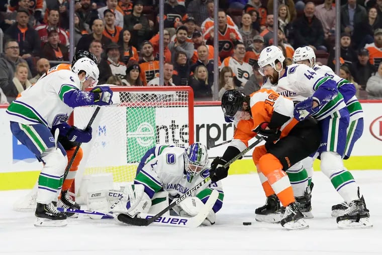 Nolan Patrick tries to get the puck past Vancouver goltender Jacob Markstrom and defenseman Erik Gudbranson (right) during the first period Monday. The Flyers won, 2-1, for their eighth straight victory.