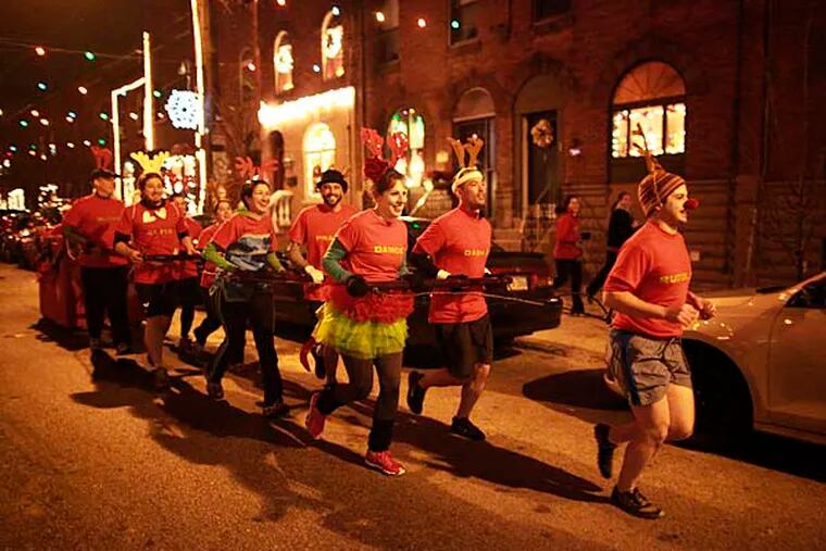 Pulling a sleigh, Dave Mavier, 25 as Rudolph leads, Christina George, William Campbell, Carolyn Redmond, Anthony LoCicero and other reindeers down Wolf street on a 3.5 mile beer run December 13, 2012. ( DAVID SWANSON / Staff Photographer )