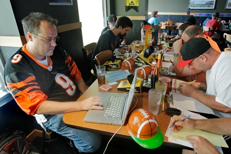 Brian Sherman, left, using his laptop to record moves in his team's fantasy football draft, at a Buffalo Wild Wings restaurant in Cincinnati.