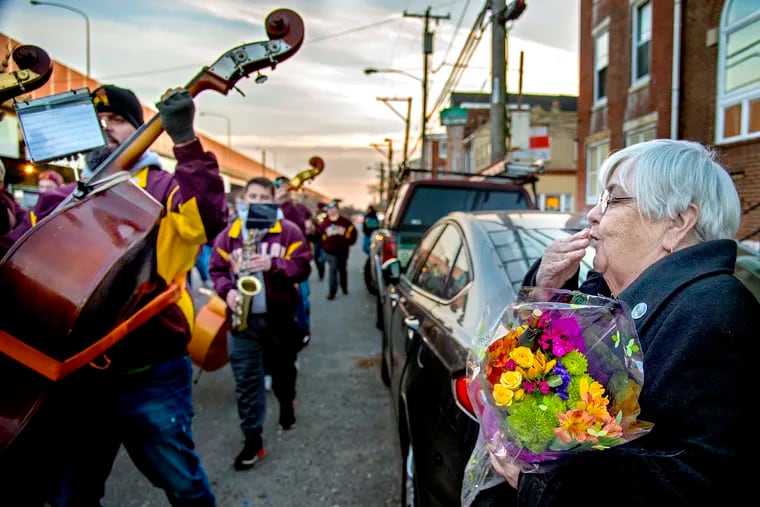 Delores Kubiak blows a kiss to the Avalon String Band after they presented her with flowers and serenaded her outside her home Sunday.  The band has done so for the past five Decembers, after her son Michael Kubiak, Jr., a band member and 17th District Philadelphia Police Officer died of suicide in 2012.