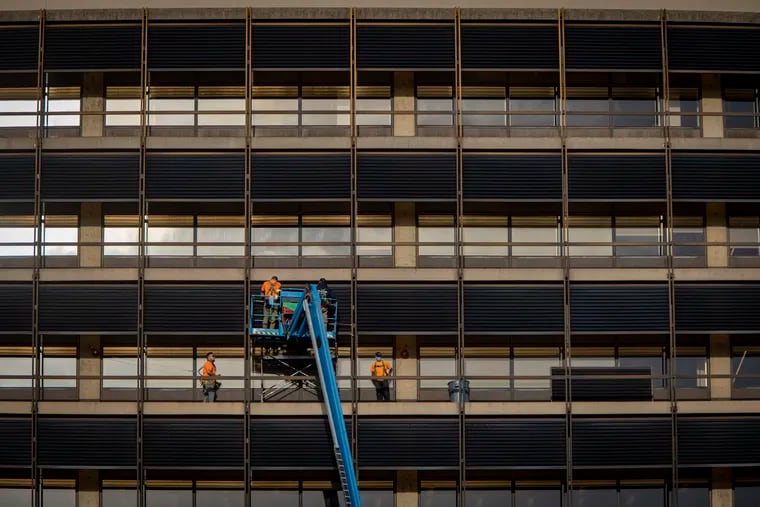 Worker with lift working on the exterior of 100 Independence Mall, where the Inquirer newspaper aims to make its future home.