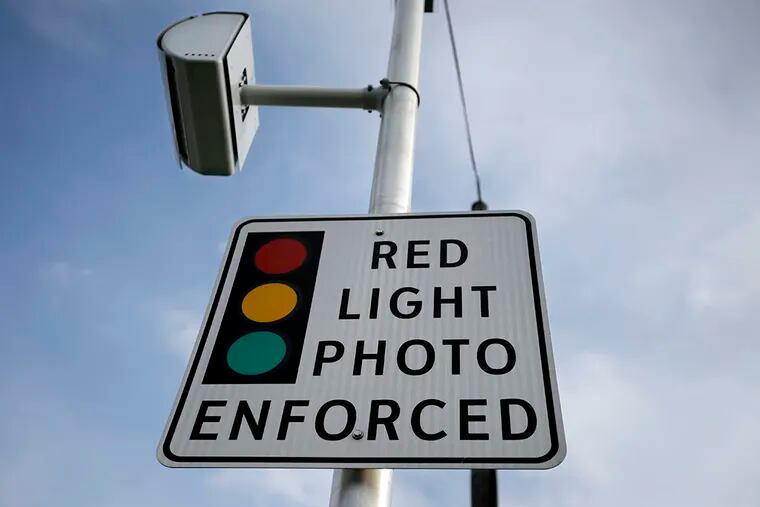An enforcement sign is seen below a red-light camera Tuesday, Dec. 16, 2014, in Lawrence Township, N.J. (AP Photo/Mel Evans)
